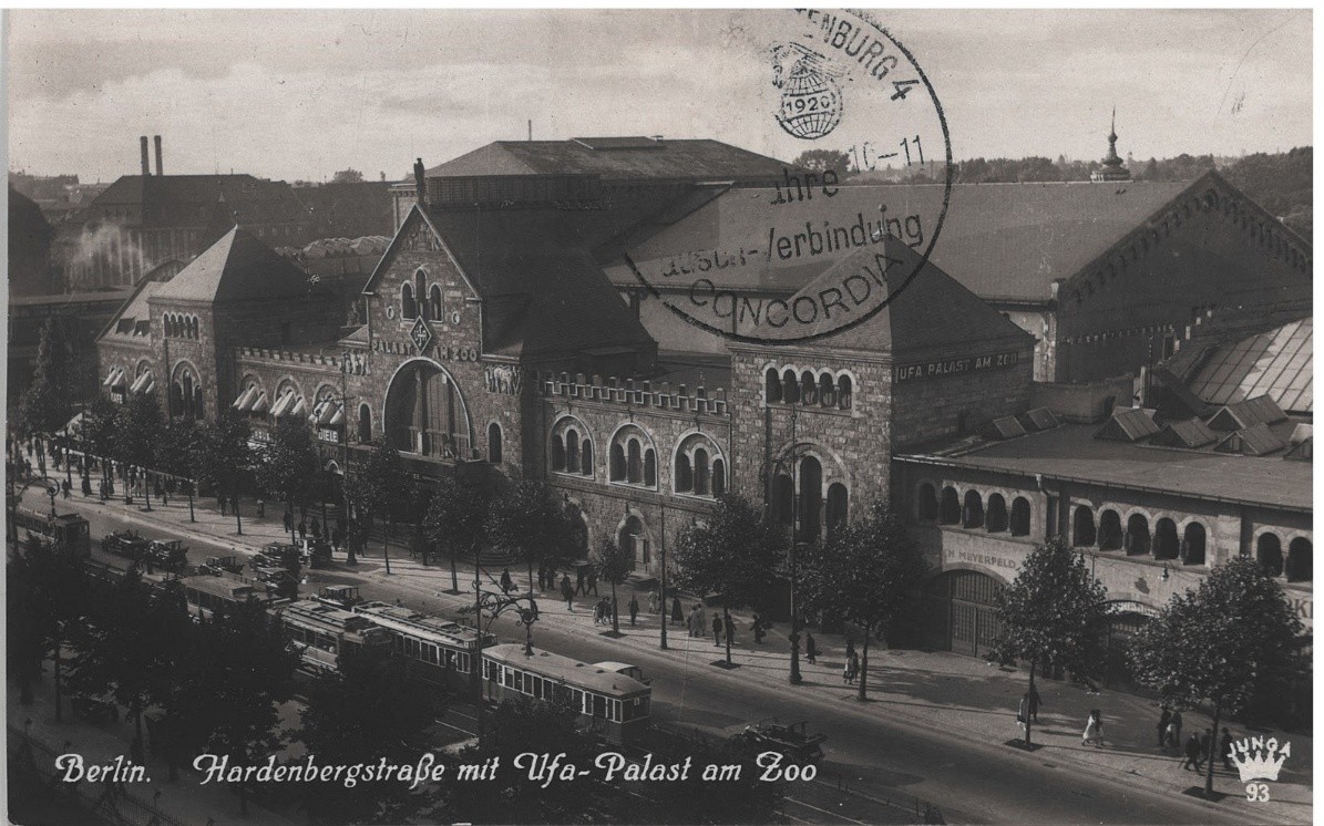 Photographic postcard captioned "Berlin. Hardenbergstrasse mit Ufa-Palast am Zoo": a long brick building with rows of arched windows, trams and cars passing in front, a postmark stamped across the sky
